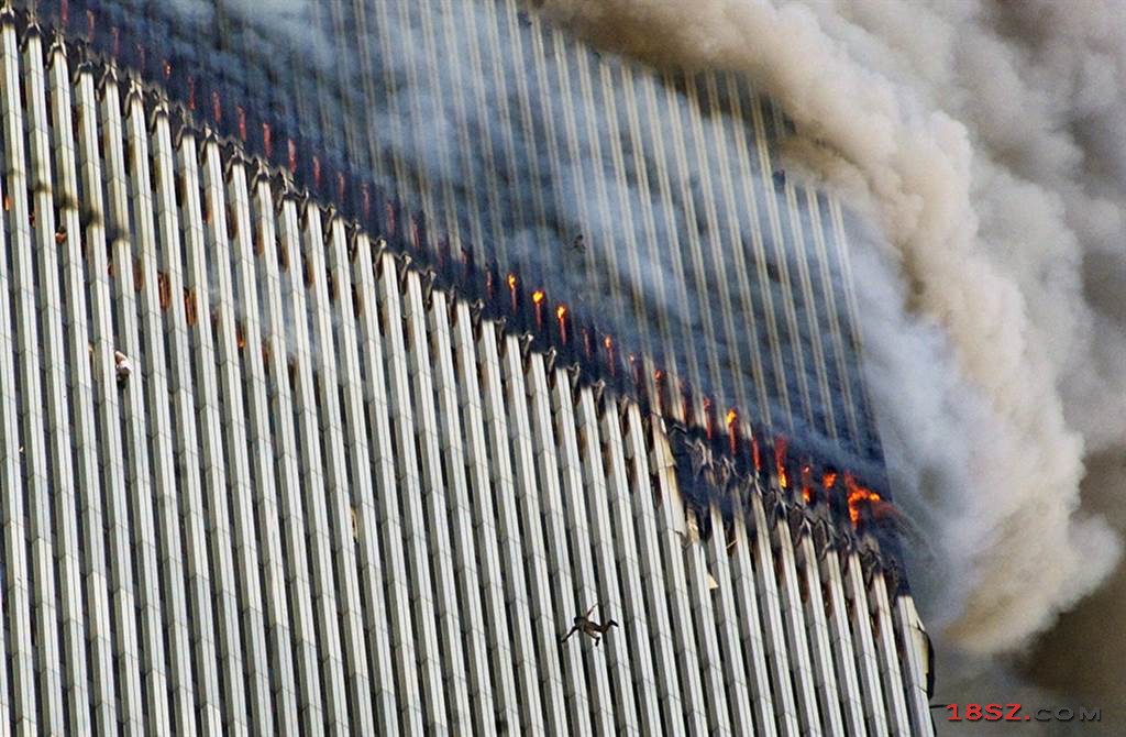 火焰及浓烟不断从双子星大楼北塔窜出，有一个人从高楼中摔下来，画面左边有另一个人紧紧攀着大楼外墙。（图／美联社）